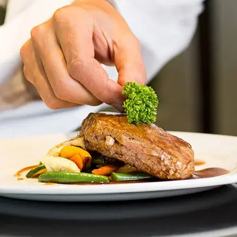 Hawthorn Senior Living Chef Created Meals, chef garnishing a plate.