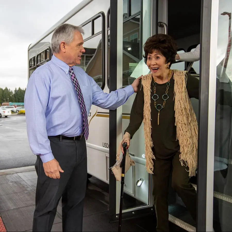 The Carriage House man helping lady off bus